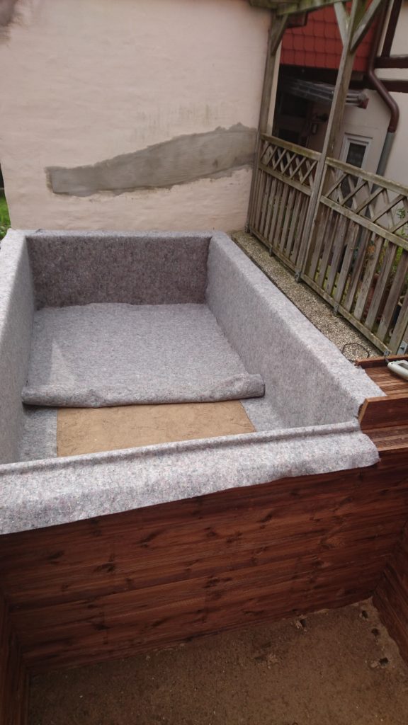 Vor der Teichfolie kommen Schutzmatten auf dem Holz und Boden